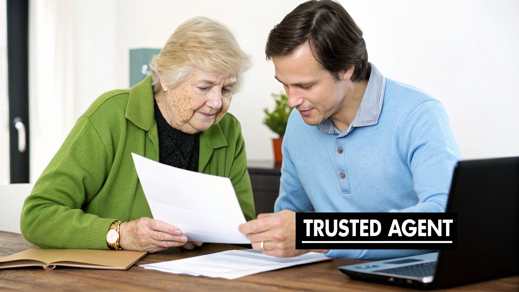 An elderly woman and a younger man, a trusted agent, review important documents at a desk.