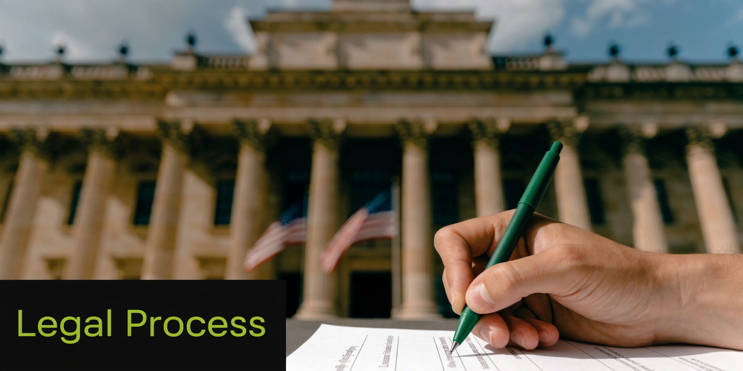 A hand signing a document with a green pen in front of a grand courthouse building.